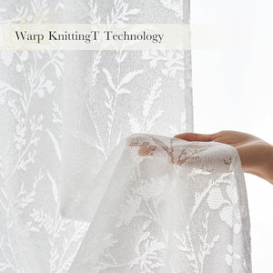 Hand holding white sheer lace curtain with intricate floral warp-knit patterns, showing transparency.