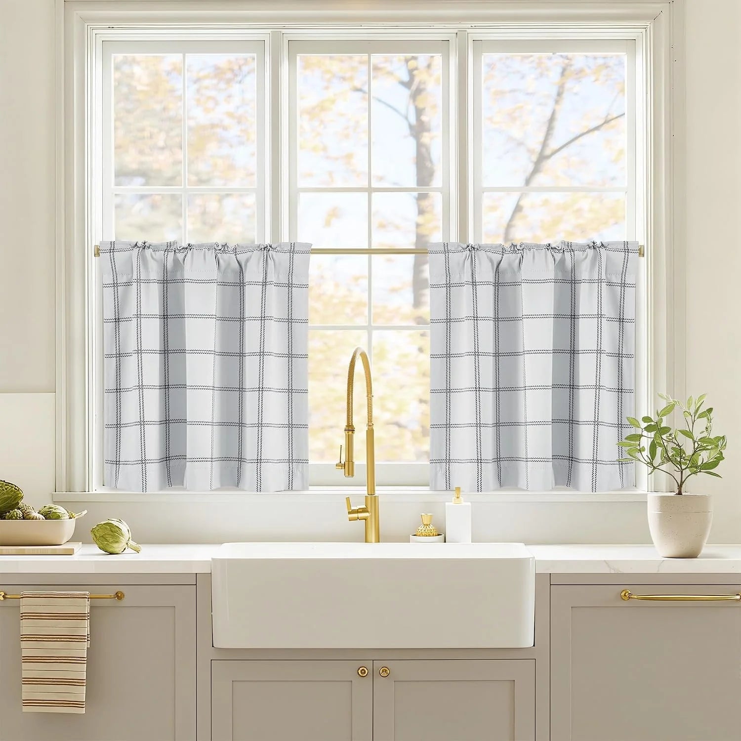 White windowpane tier curtains over a farmhouse kitchen sink with brass faucet