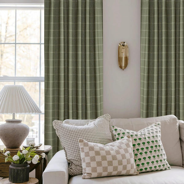 Woven sage green plaid pinch pleat curtains framing a window in a cozy living room.