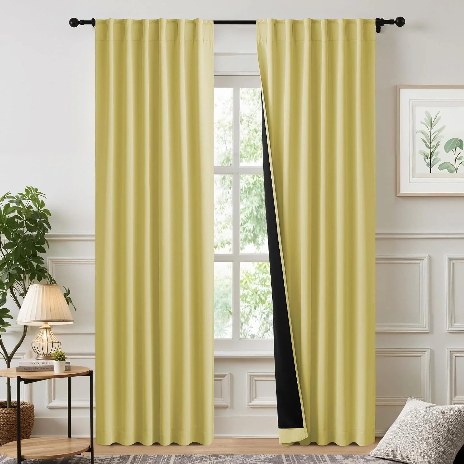 Pale yellow blackout curtains with rod pocket top hanging on a black curtain rod